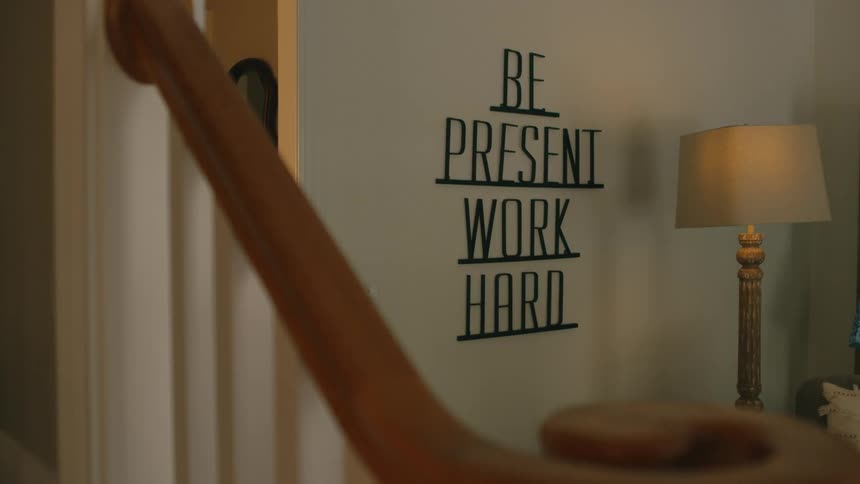 Close up of a sign with an inspirational quote hanging from the wall on the living room