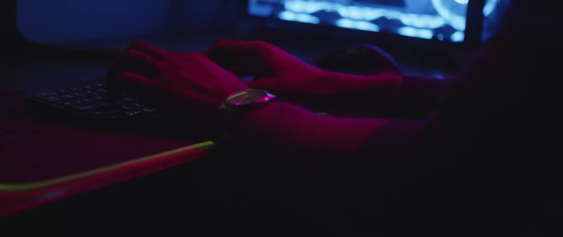 Close up of the hands of a man typing on a computer keyboard under changing rgb lights