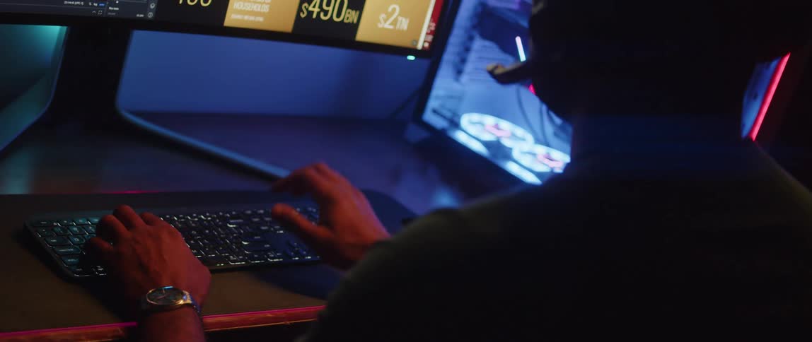 Man with headphones works on computer next to pc case in dark room