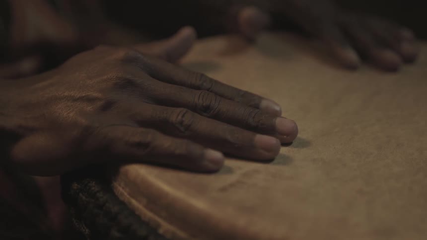 Two hands lay on the surface of a drum