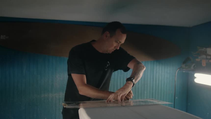 A man is using a plastic template to mark on wood with a pencil