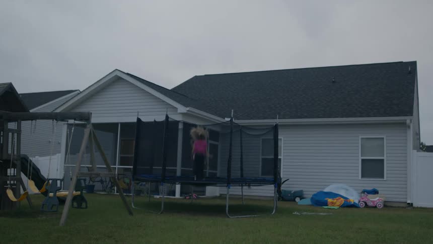 A view of two kids jumping on a trampoline