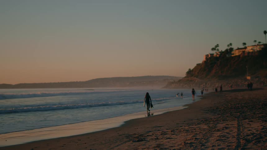 People on vacation walking on the sand next to a beach at sunset