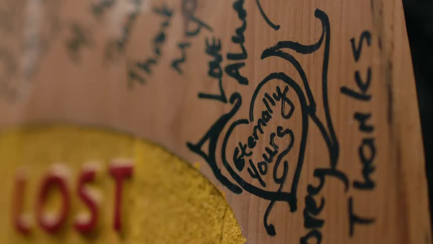 A handwritten love note on a wooden plaque with a black marker