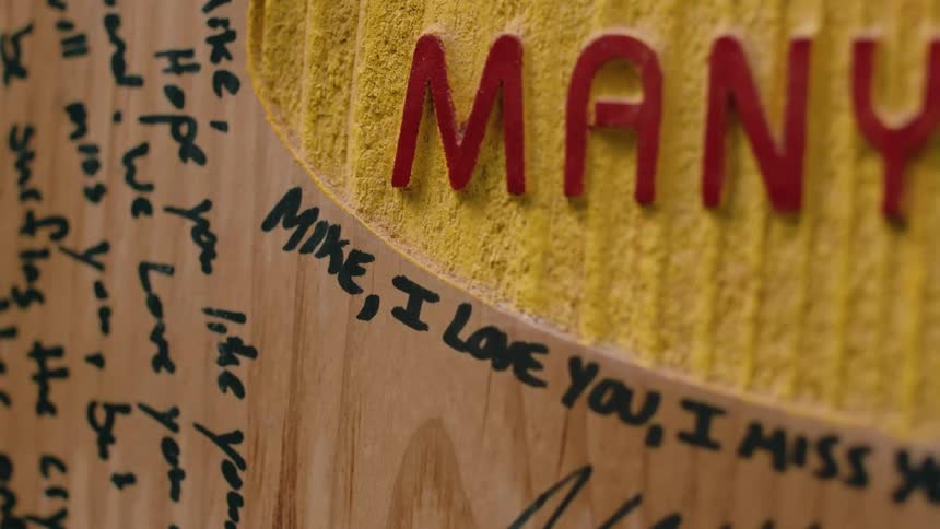 A handwritten love note is on a wooden sign with a black marker