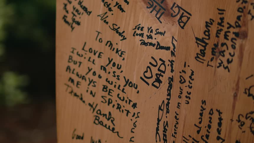 Handwritten messages in marker cover a portion of a wooden fence