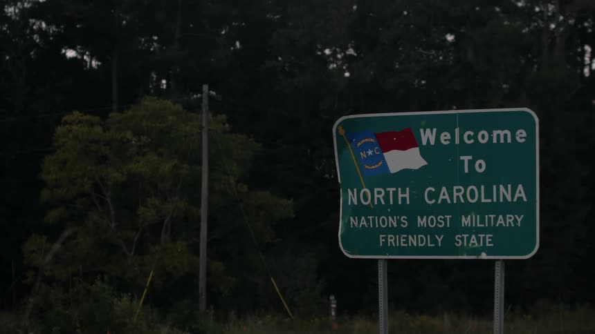 Vehicles driving along highway pass north carolina state line welcome sign