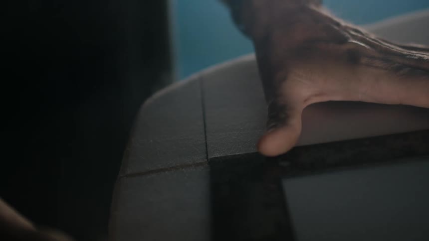 A man is using a right angle to draw a line on a piece of wood