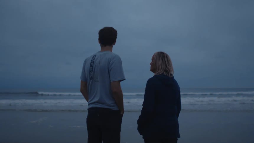 A man and woman talk while standing on a beach on a cloudy evening