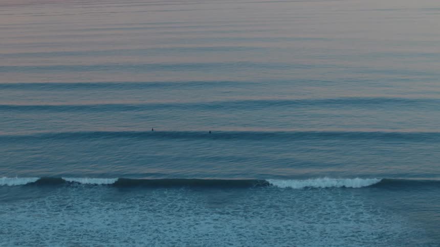 Two people are in the water as waves roll into shore
