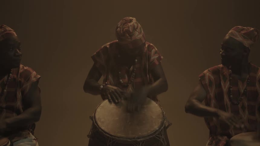 Three people play drums together