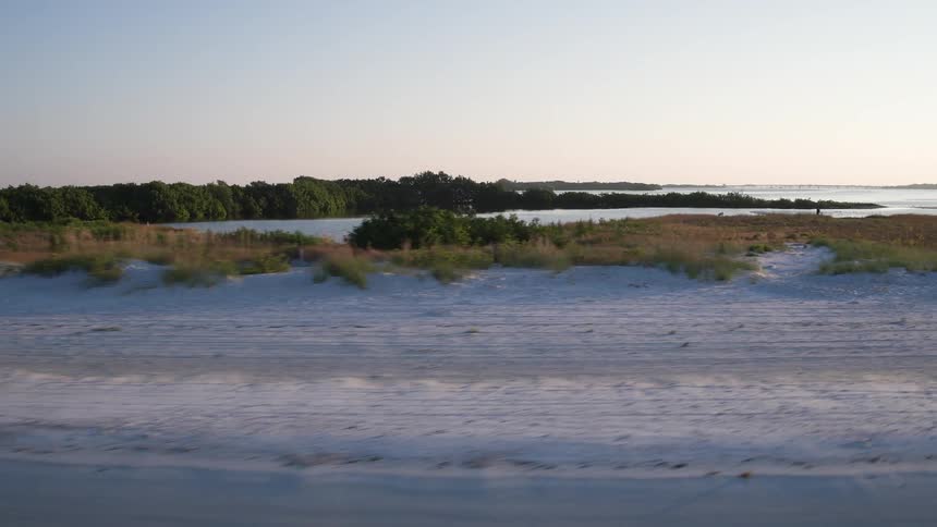 The shore is covered with grass and sand