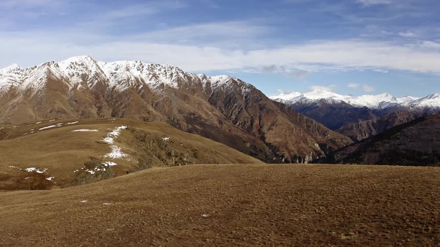 The native grass covered hills lead to the mountain range