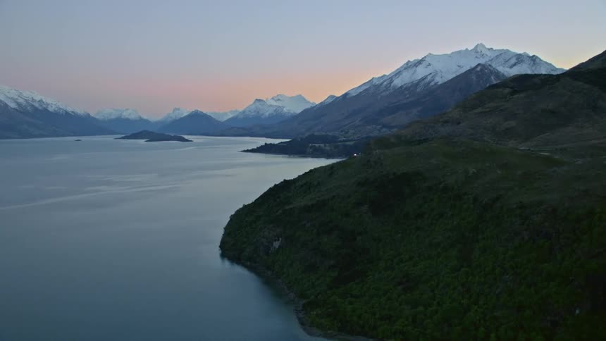 Aerial view of mountains at dawn with calm alpine lake