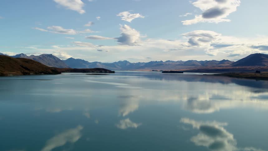 Clouds floating above a calm lake surrounded by mountains