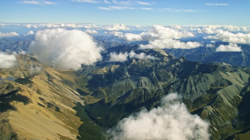 Aerial view of barren mountain range over clouds floating