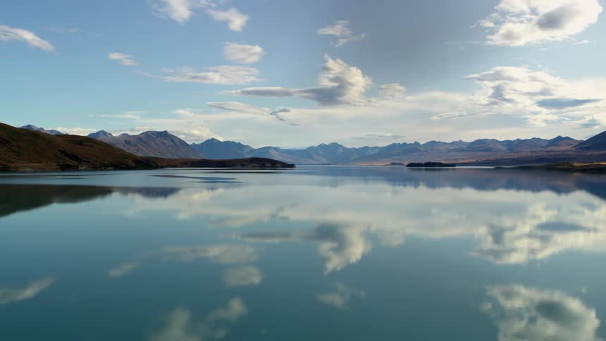 Clouds floating above a calm lake surrounded by mountains in nature