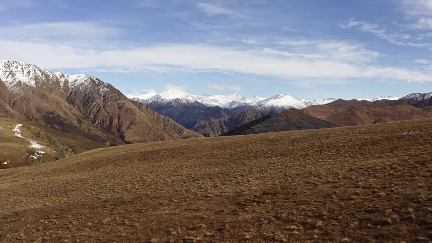 Aerial view of barren mountain slope and distant snowy mountain range