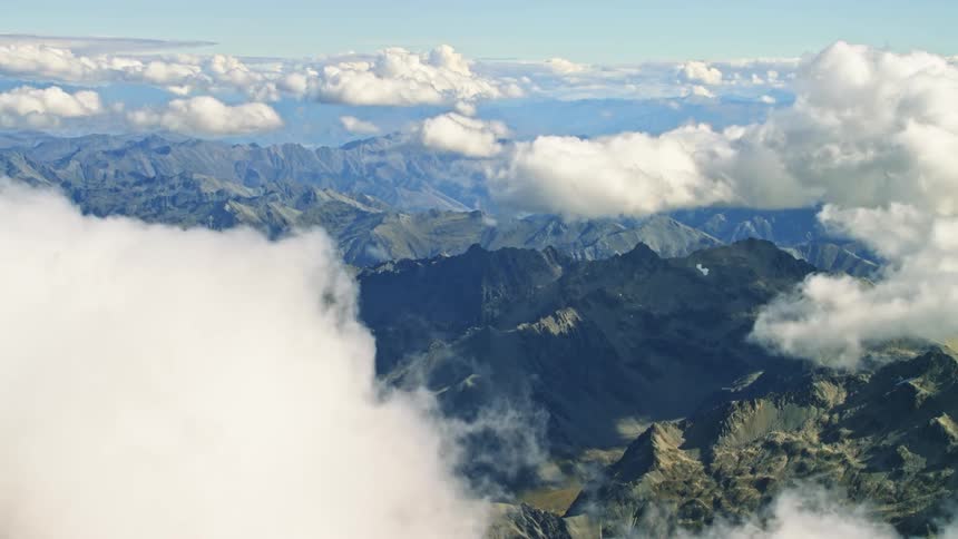 An aerial view of clouds floating above a mountain range in the wilderness