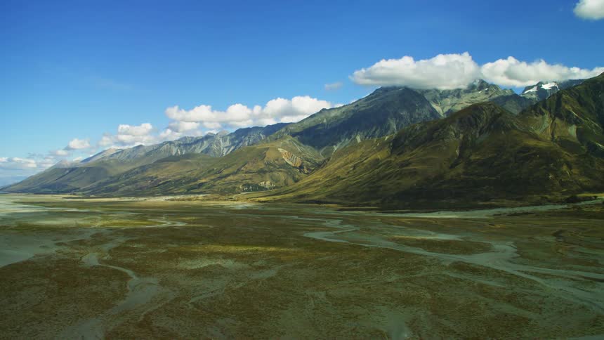 A bright blue sky and white clouds over mountain peaks and ridge