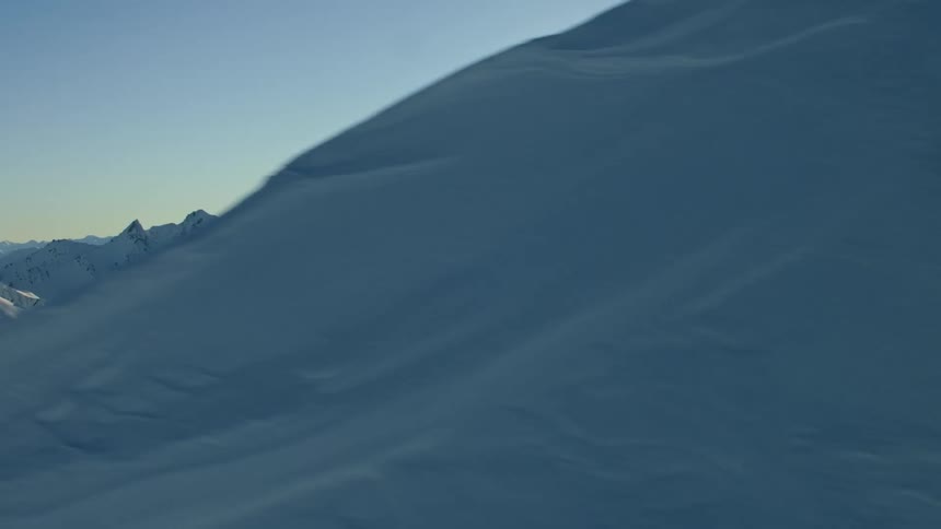 A snow covered mountain ridge with the sun shining brightly in the sky