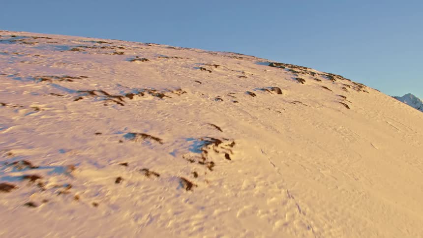Aerial view of sun shining on snowy mountain slope