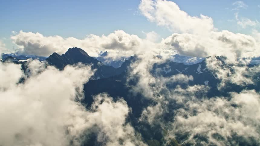 An aerial view of clouds floating above a mountain range in nature