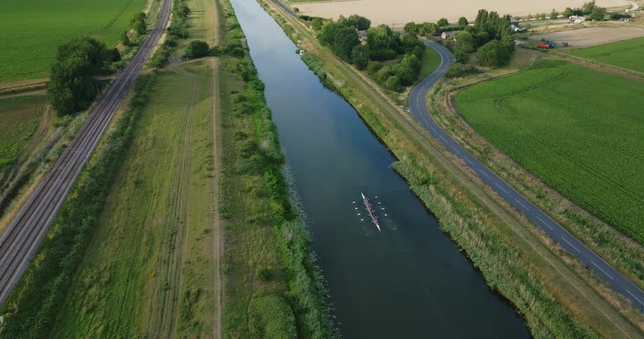 An aerial view of a rowboat traveling down a rural river