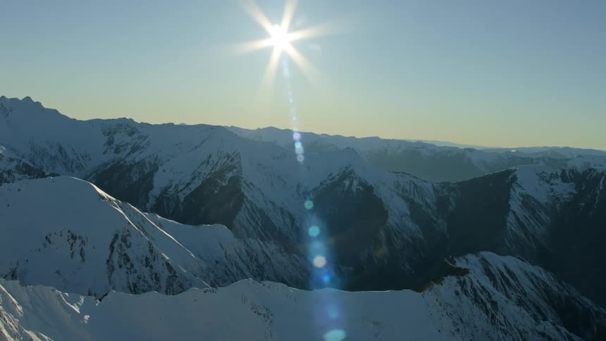 The sun shining over snowy mountains in the morning