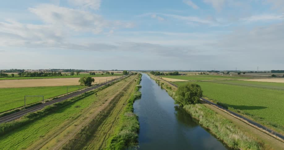 An aerial view of a river running through rural fields with a train track running alongside