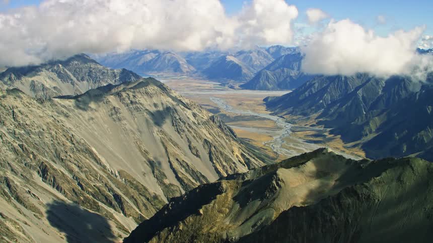 An aerial view of clouds floating above a mountain range