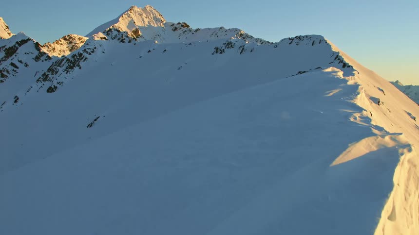 A snow covered mountain ridge with shadow on one side and sunlight on the other slope