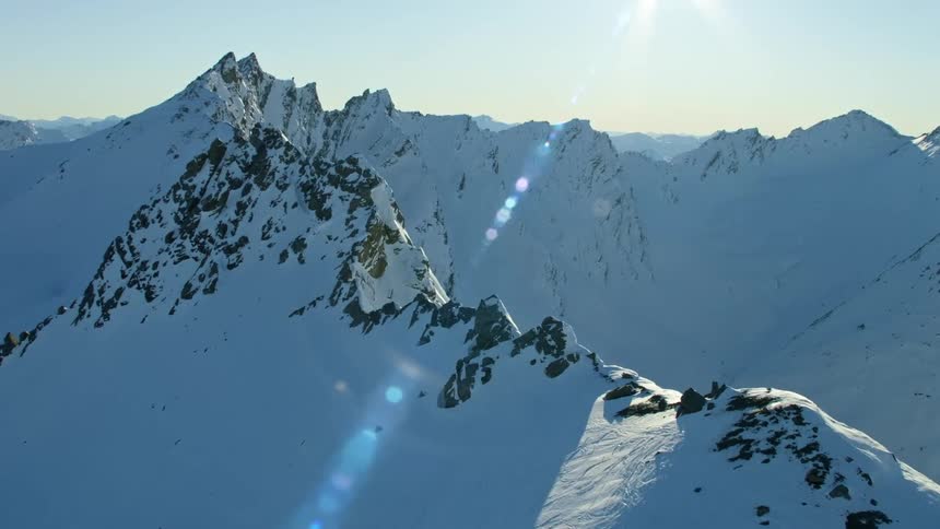 Sunlight shining over a snowy mountain range in the morning