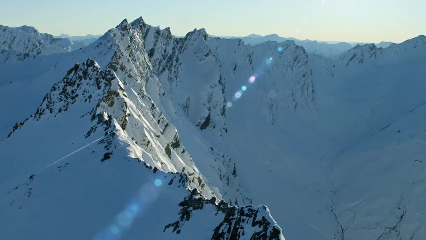 The sun shining on snow covered mountain ridges