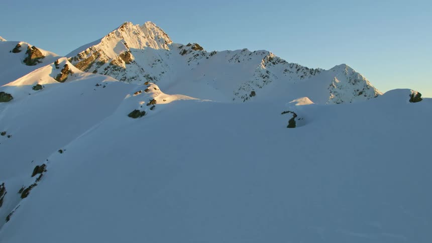 An aerial view of snowy mountains at sunrise