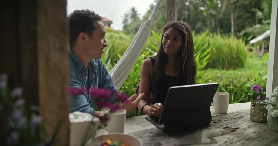A woman smiles and laughs while talking with a man during a meeting on a deck