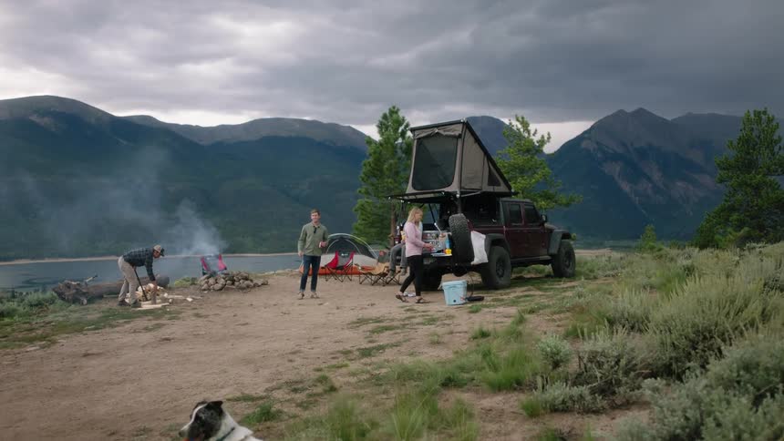 People are camping by the lake with their dogs