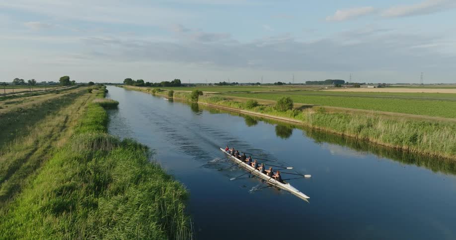 An aerial view of people rowing on a boat on a rural river