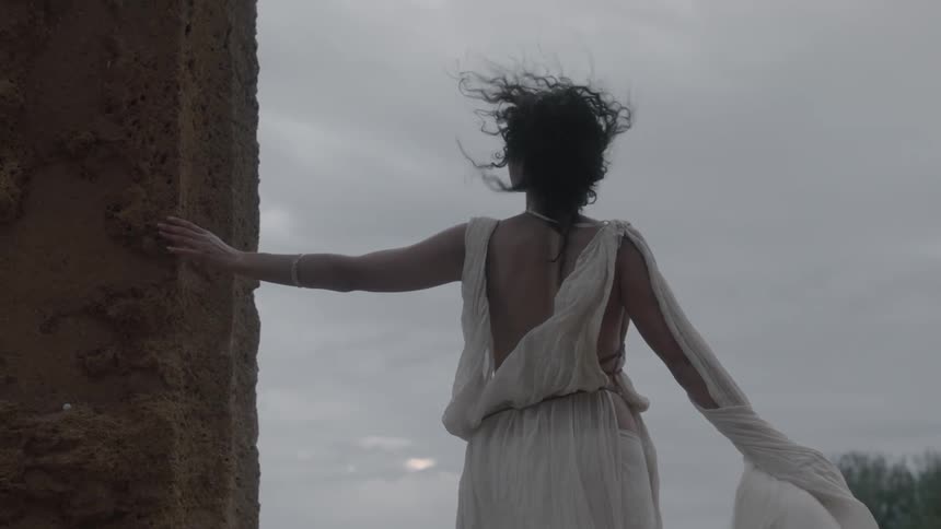 A woman stands outside on a windy day