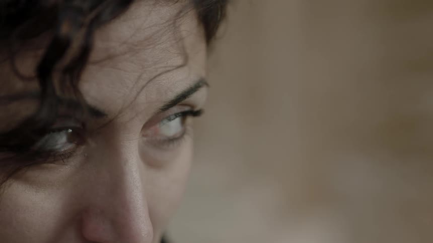 Wisps of hair blow around a woman's eyes