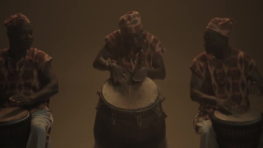Three people play drums together