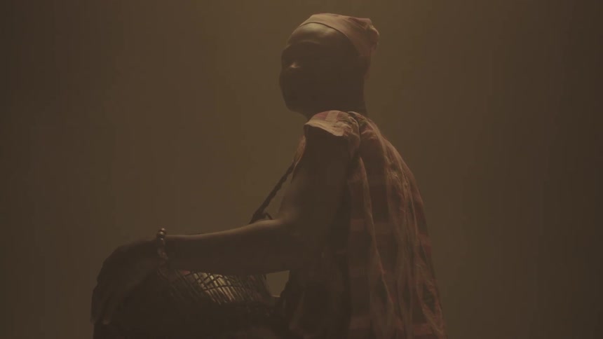 A man holding a bongo against his side raises his head