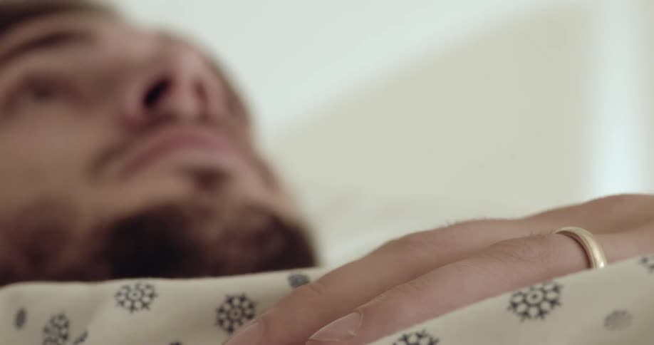 A man is lying in bed taping his finger on his chest