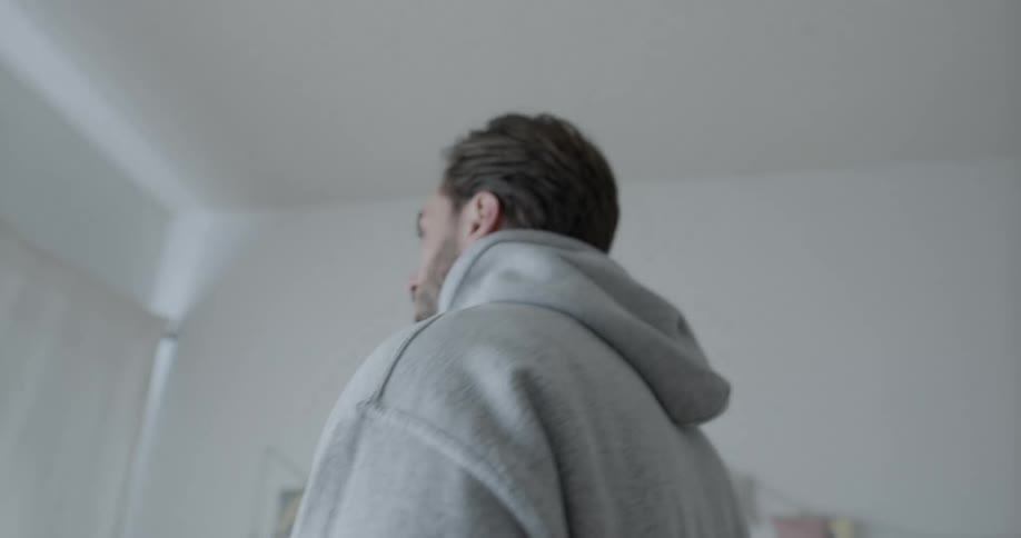 Man with beard and gray hoodie stands in room