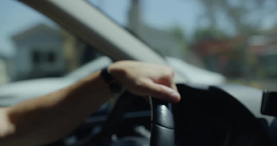 Man with jeans blue shirt and watch drives car in neighborhood