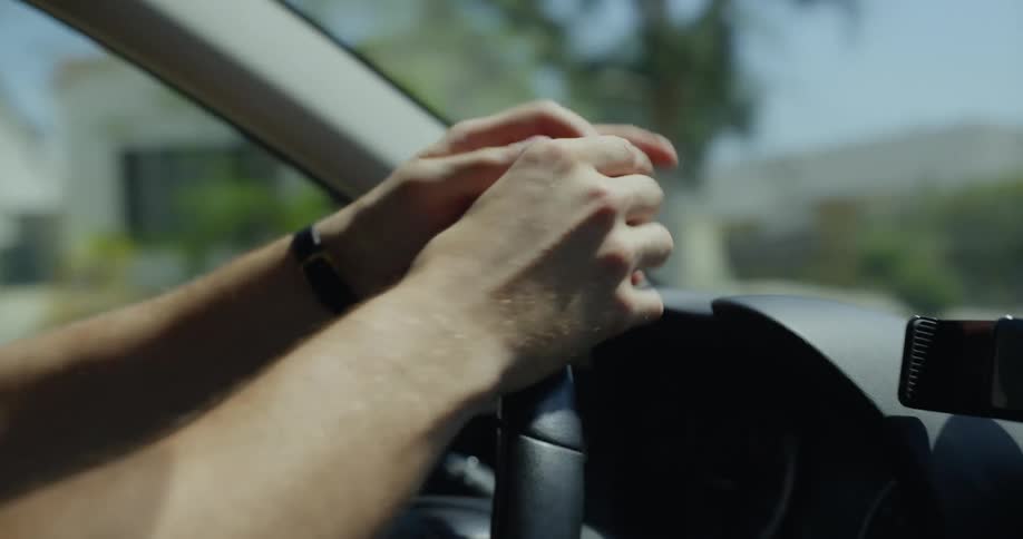 Close up of the hands of a man driving a car changing a ring from one finger to another