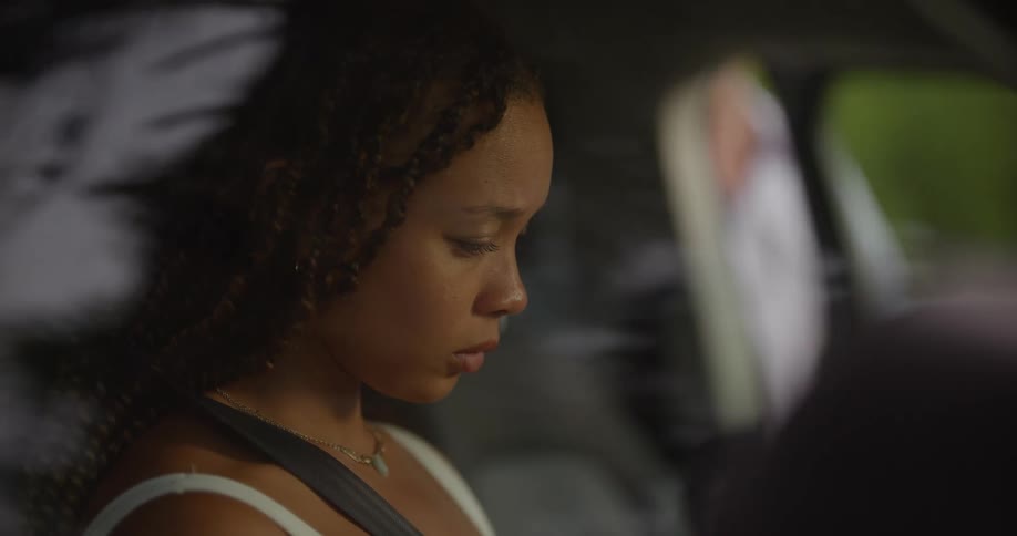 Man enters a car where a young sad woman is sitting on the passenger seat