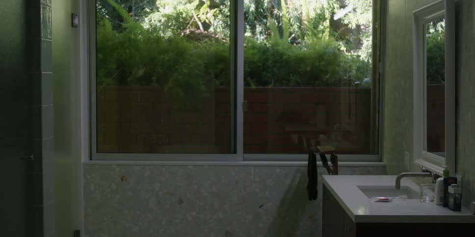 Green lush tropical plants outside the window of a bathroom in the morning