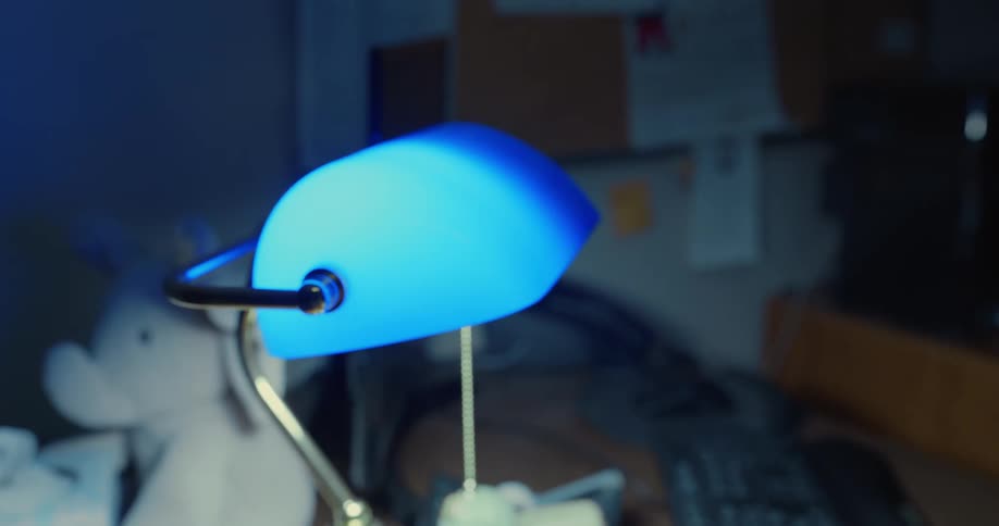 Close up of a blue lamp over a desk inside a dimly lit room
