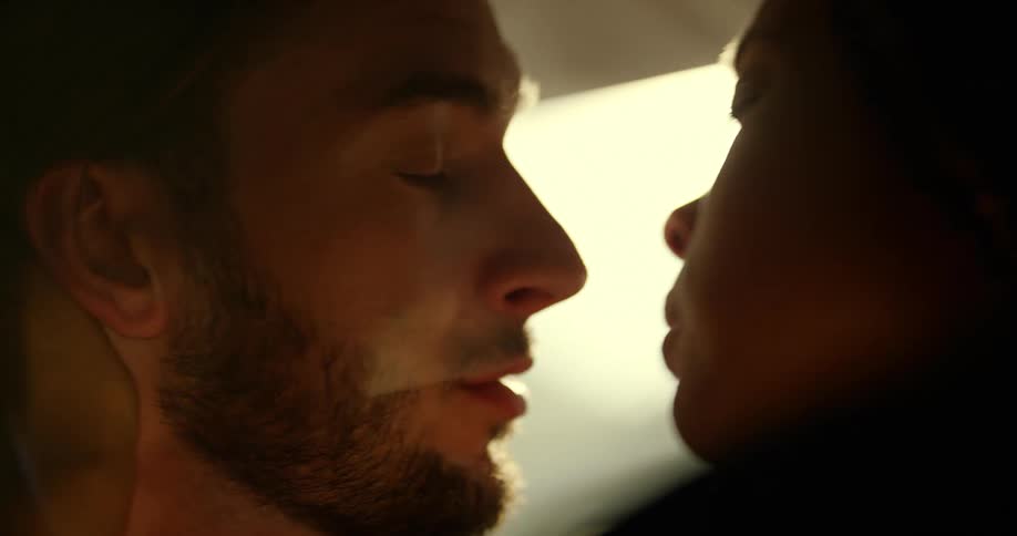 A man and woman kissing in the front seat of a parked car